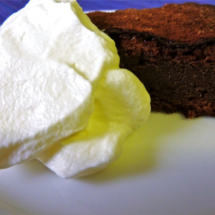 A slice of flourless chocolate cake with whipped cream